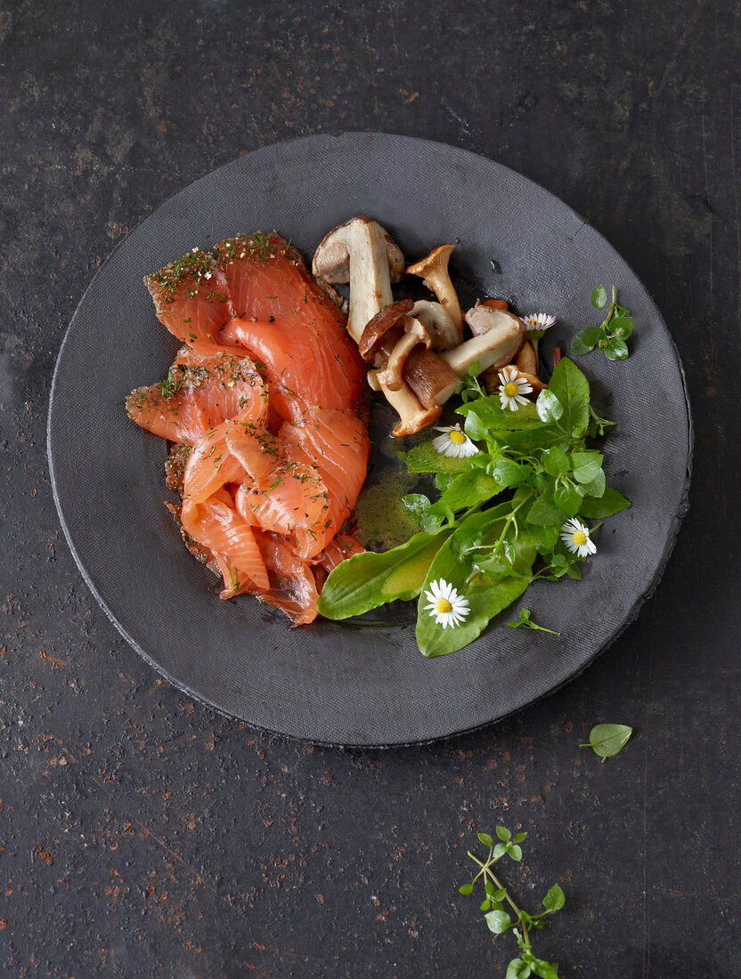 Smoked salmon with mushrooms, lettuce and daisy on plate