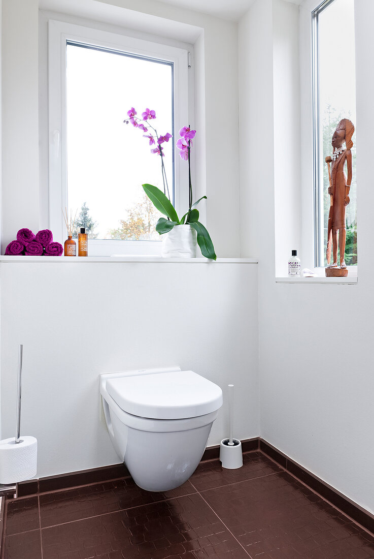 Toilet in bathroom and window sill decorated with decorative