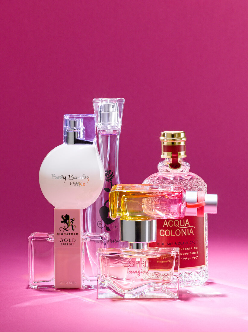 Various types of perfume bottles in Berlin style against pink background