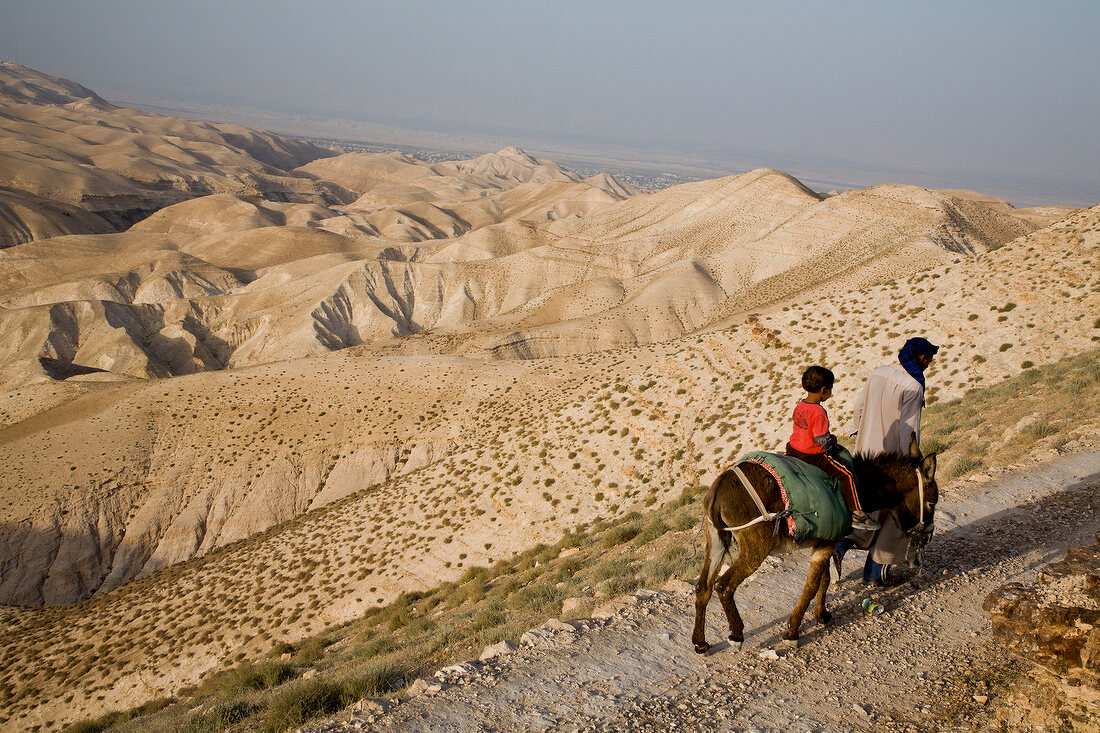 Palestinians walking with donkey on Judean desert near Jericho, West Bank, Israel