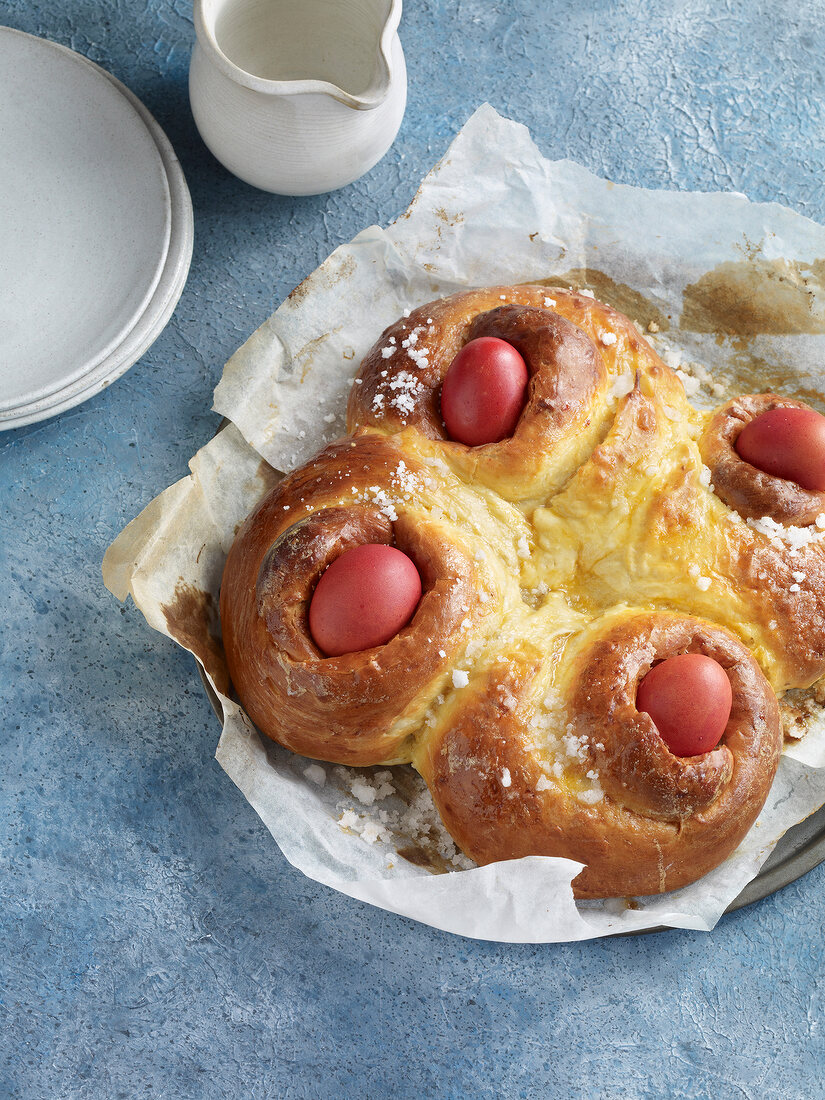 Greek Easter bread with red eggs on baking paper