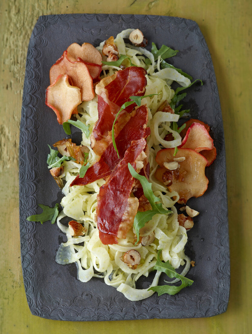 Fennel salad with nut brittle and apple chips in serving dish