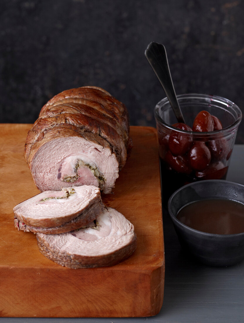 Veal roll on board, plum in glass and vinegar in bowl