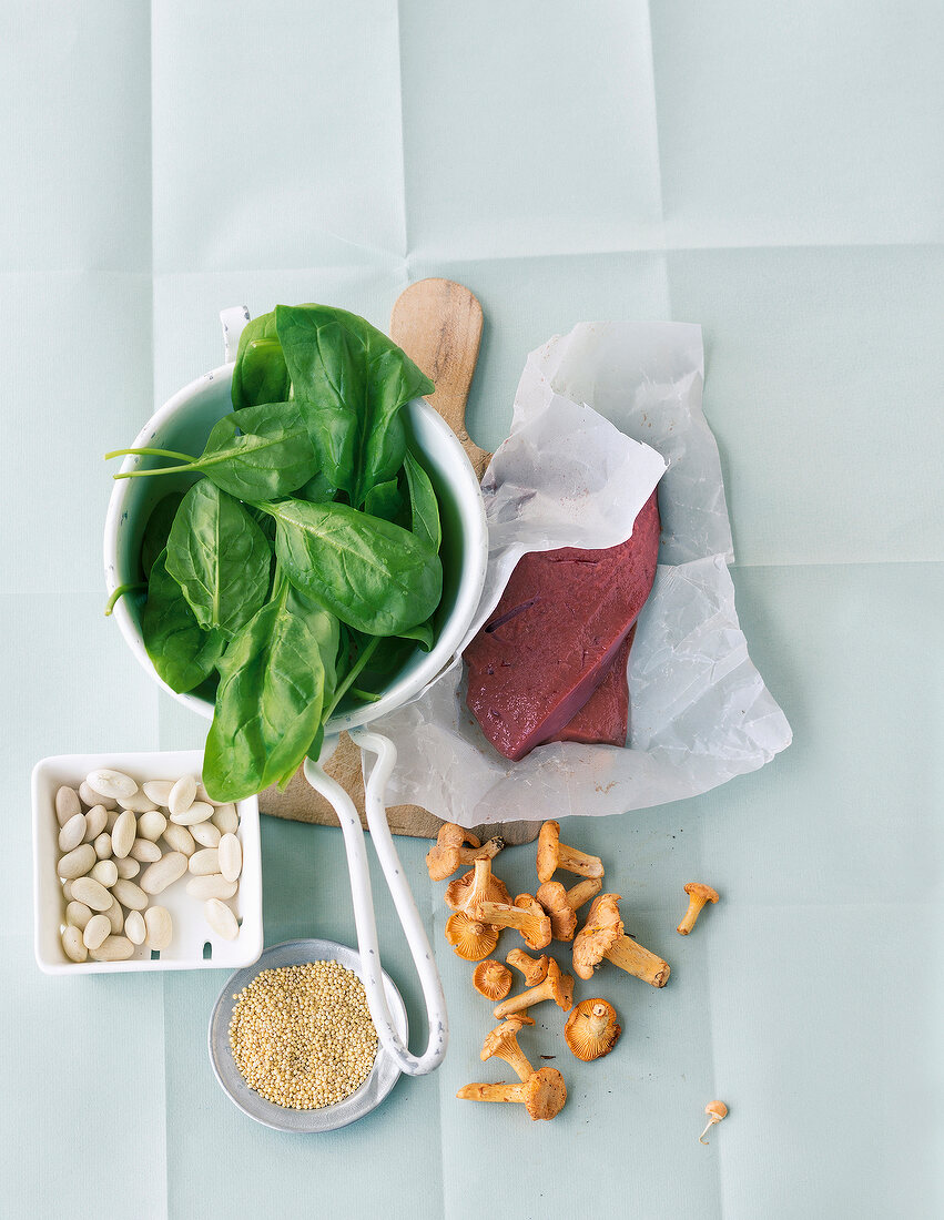 Slices of liver, beans, millets, chanterelles and spinach symbolising iron rich food