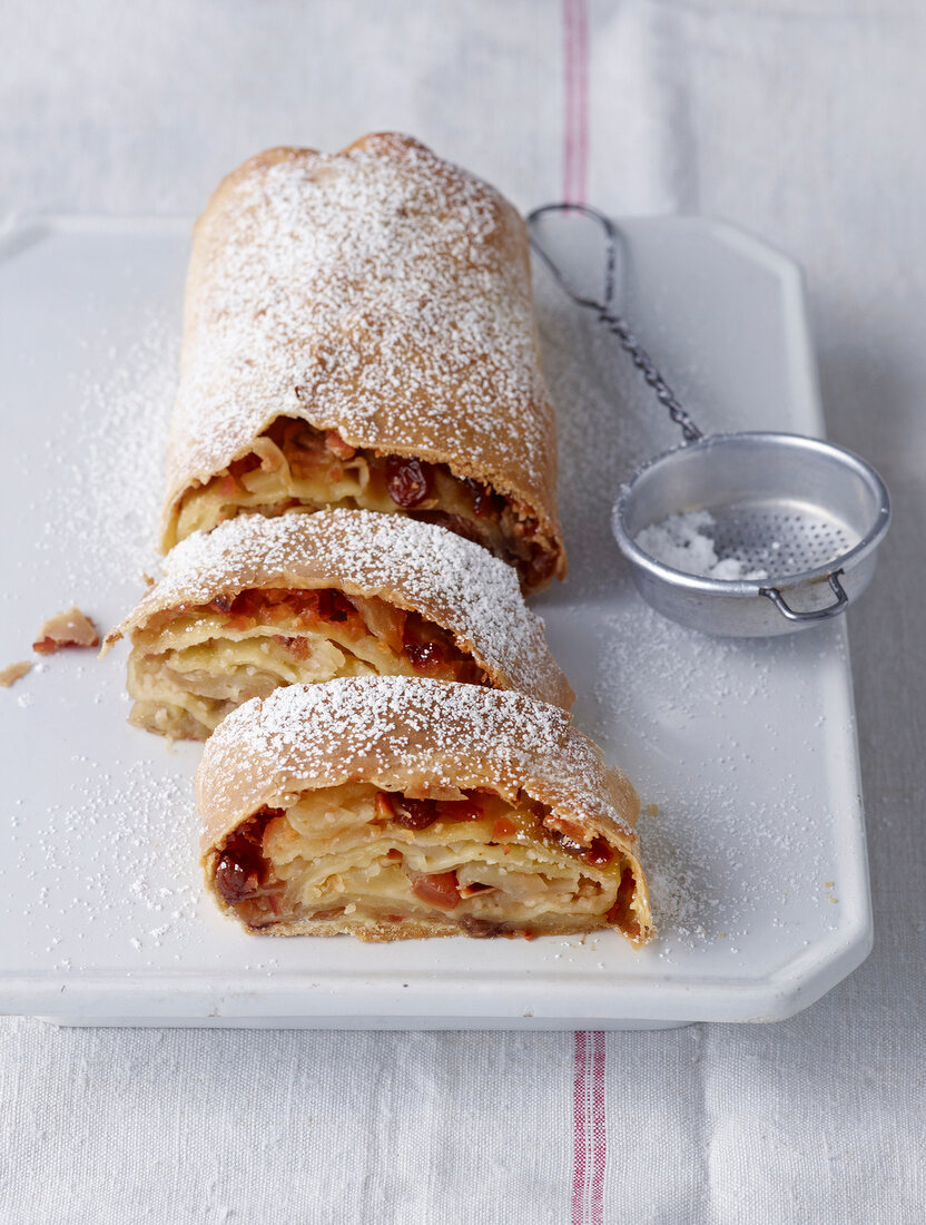 Apple strudel powdered with icing sugar and sieve on tray
