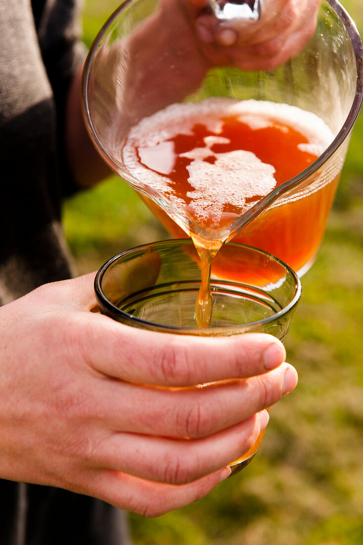 Apple juice being poured in glass at Hofmosterei Ellershausen in Hesse, Germany