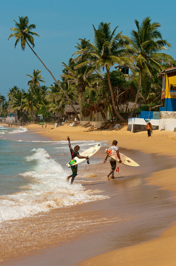 Men with surfboard on Hikkaduwa beach, Sri Lanka