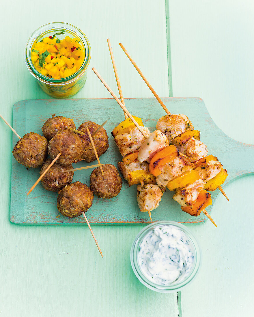 Coconut and meat skewers and chicken skewers on wooden board