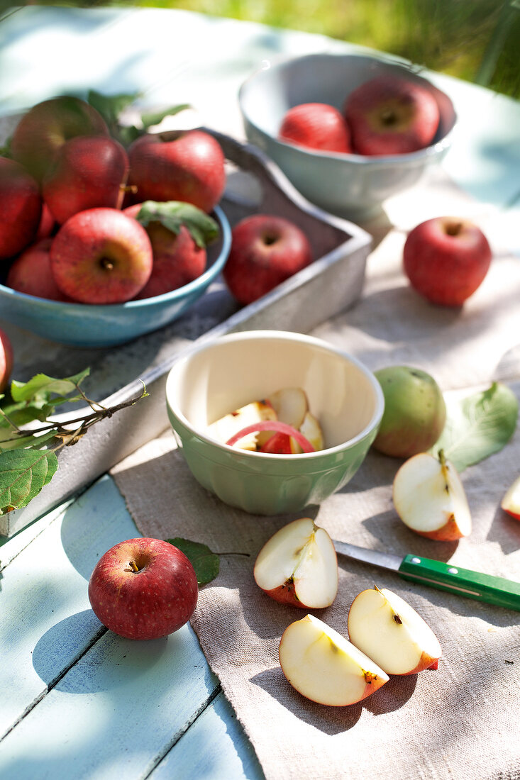 Whole and pieces of apples on bowl and tray