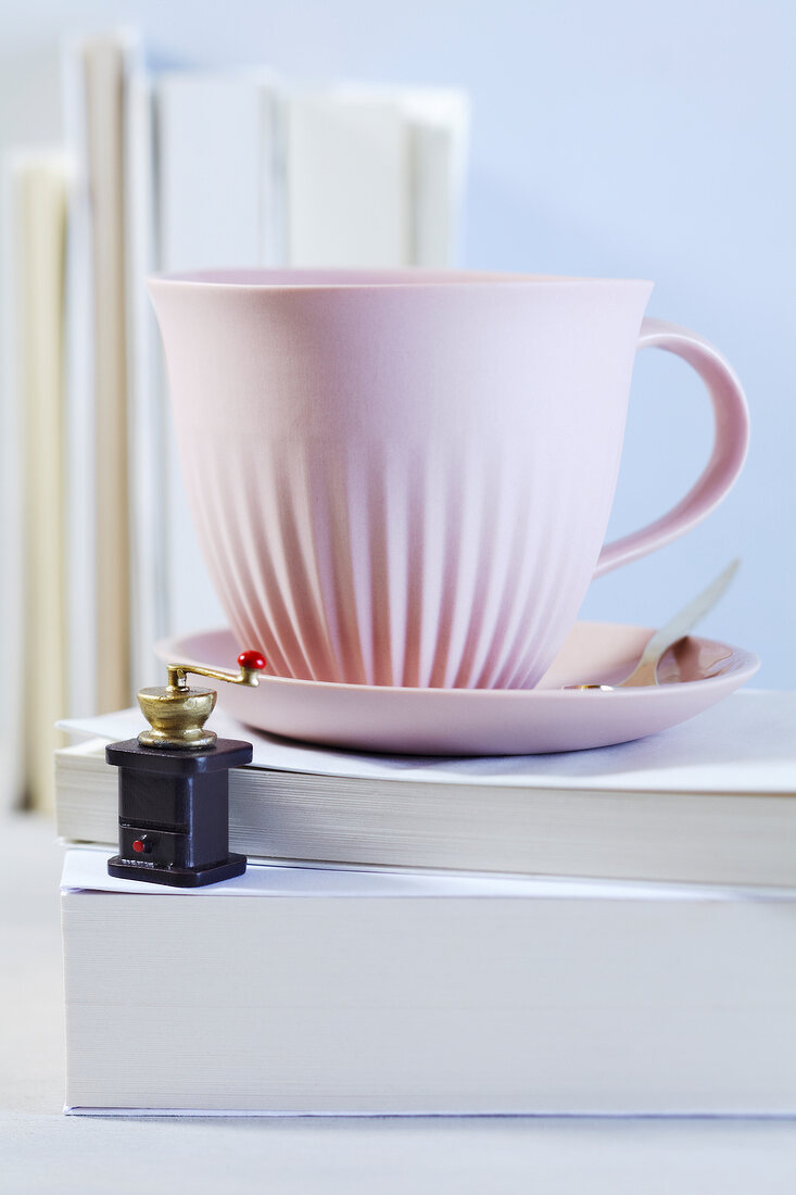 Pink teacup with miniature coffee grinder