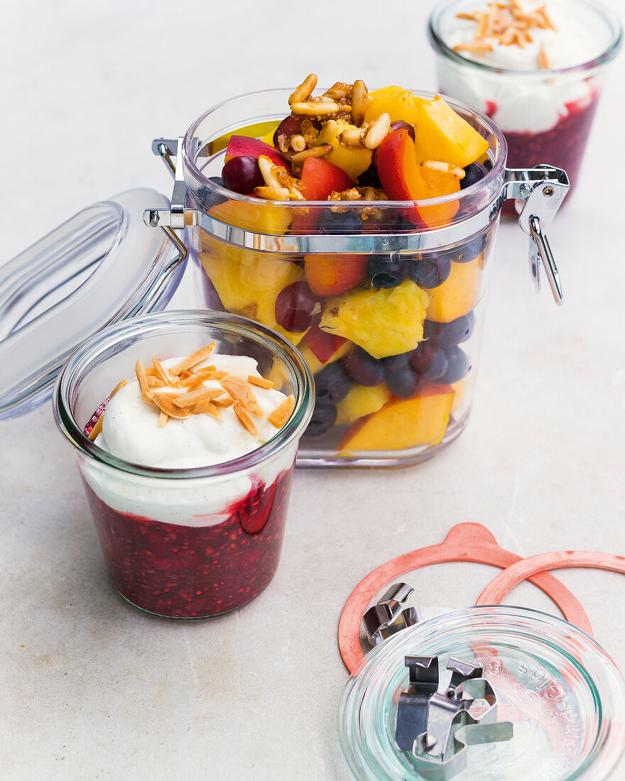 Fruit salad with candied pine nuts and raspberry compote in glass containers