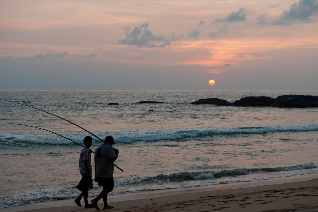 Fishermen walking on beach at sunset in Koggala, Sri Lanka