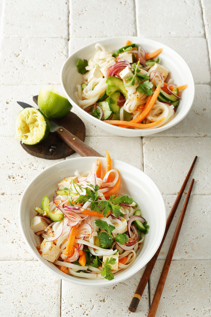 Two bowls of fruity, rice and noodle salad with chopstick