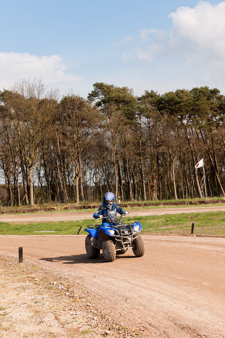 Boy riding razor blue quad dirt bike in forest 