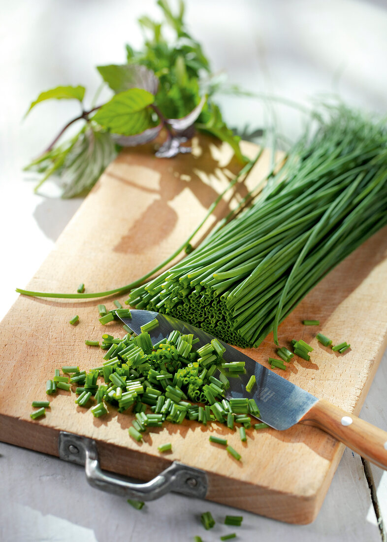 Close-up of chives being chopped on wooden board