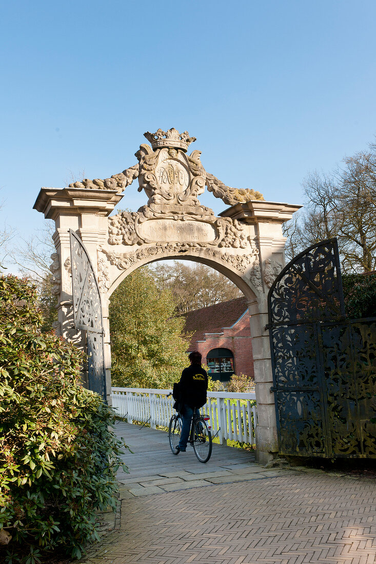 Rear view of man rising bicycle at Dankern Castle gate