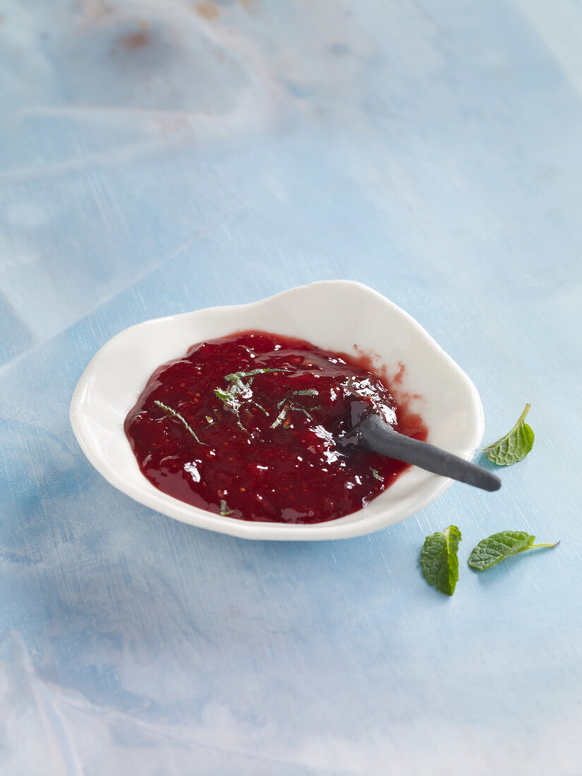 Strawberry jam with mint leaves in bowl