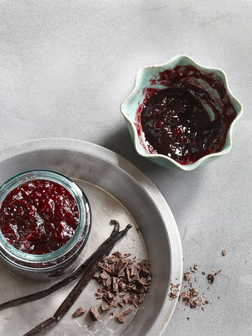 Cherry jam in jar with chocolate chips on plate