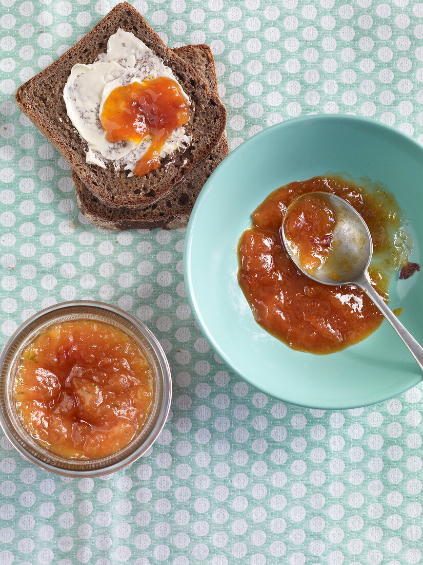 Apricot jam and peach jam in bowls and two slices of bread