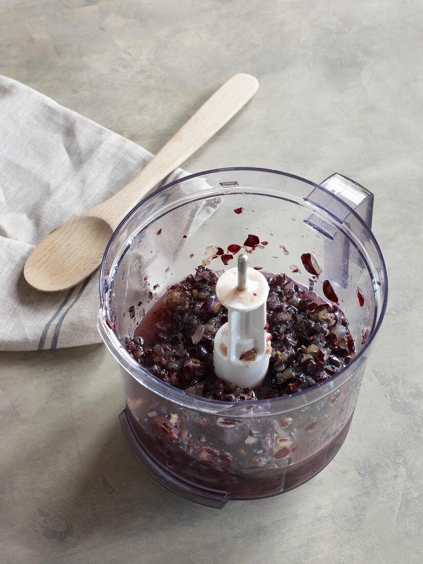 Grapes in mixer beside wooden spoon on towel for preparation of jam