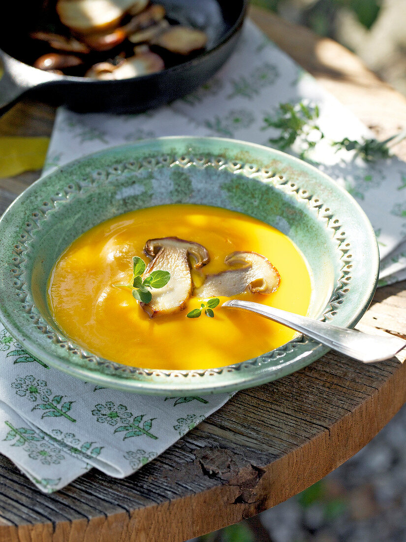 Cream of pumpkin soup with fried mushrooms in bowl