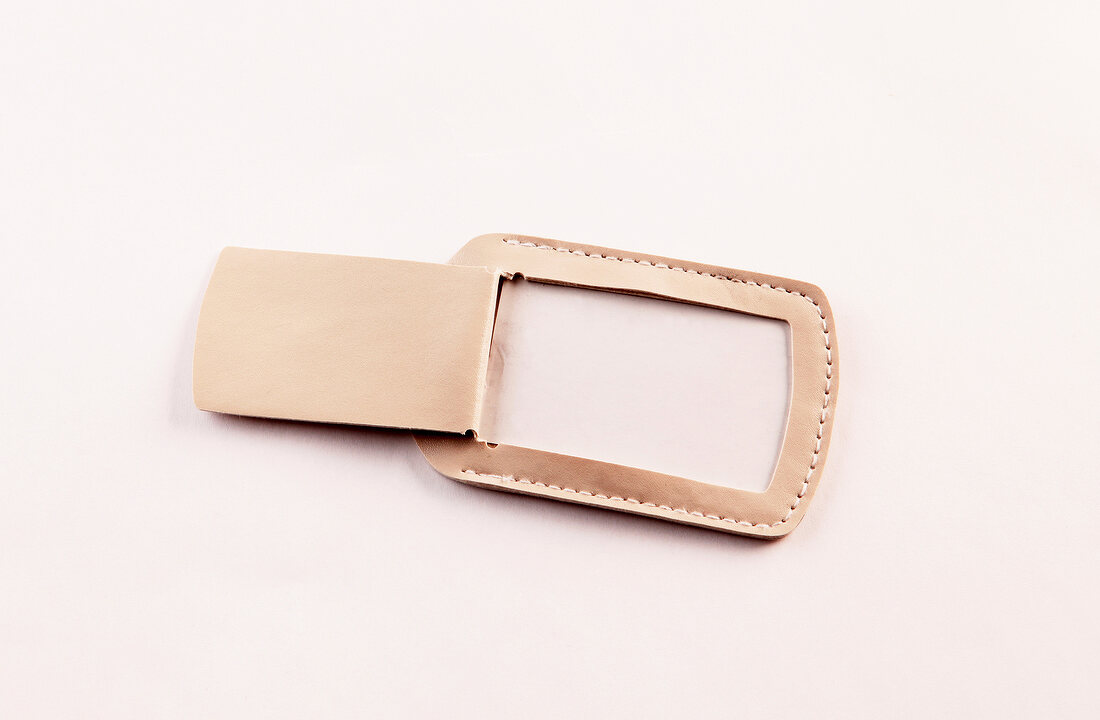 Close-up of beige leather luggage tag on white background