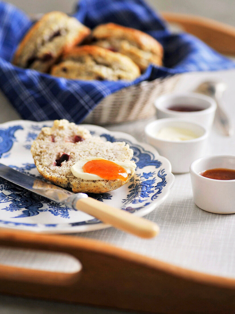 Close-up of sliced scone with clotted cream and jam on plate