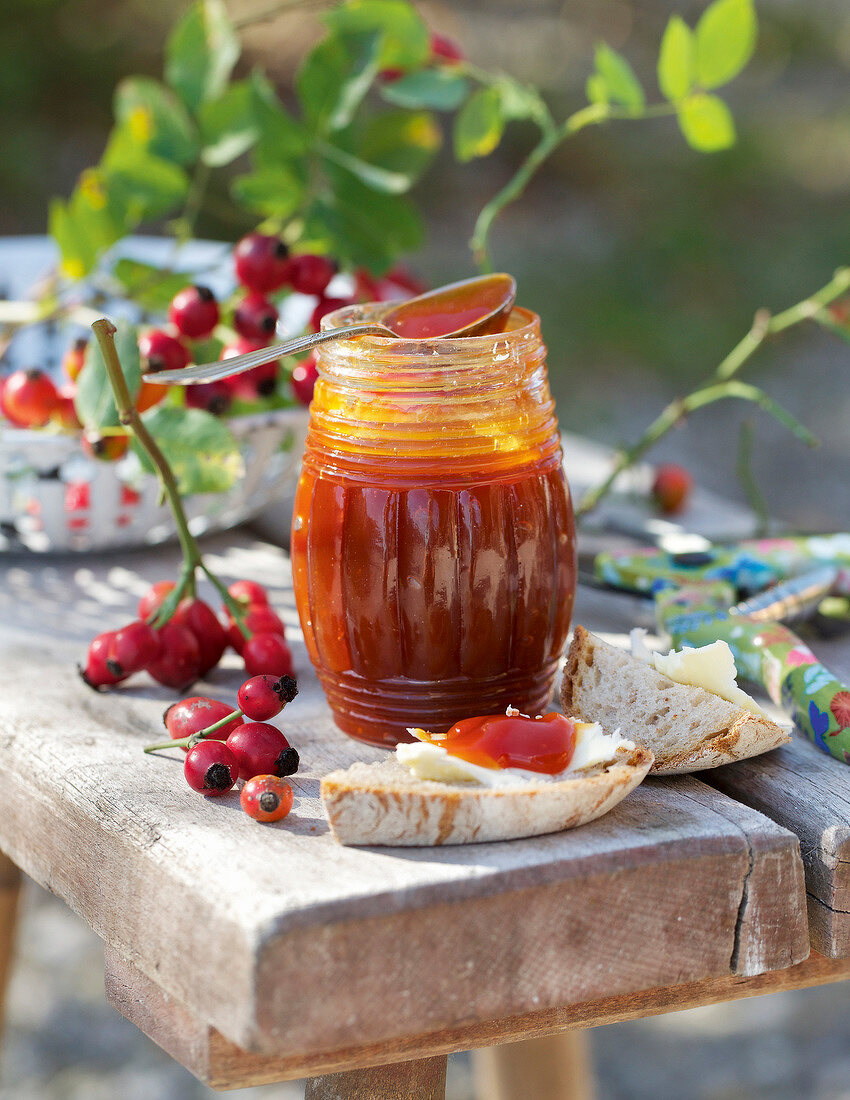 Rose hips next to hagebuttenmus in glass jar