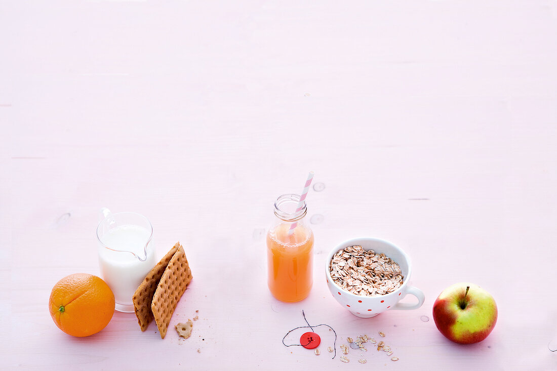 Fruits, crisp bread, milk and juice on pink background
