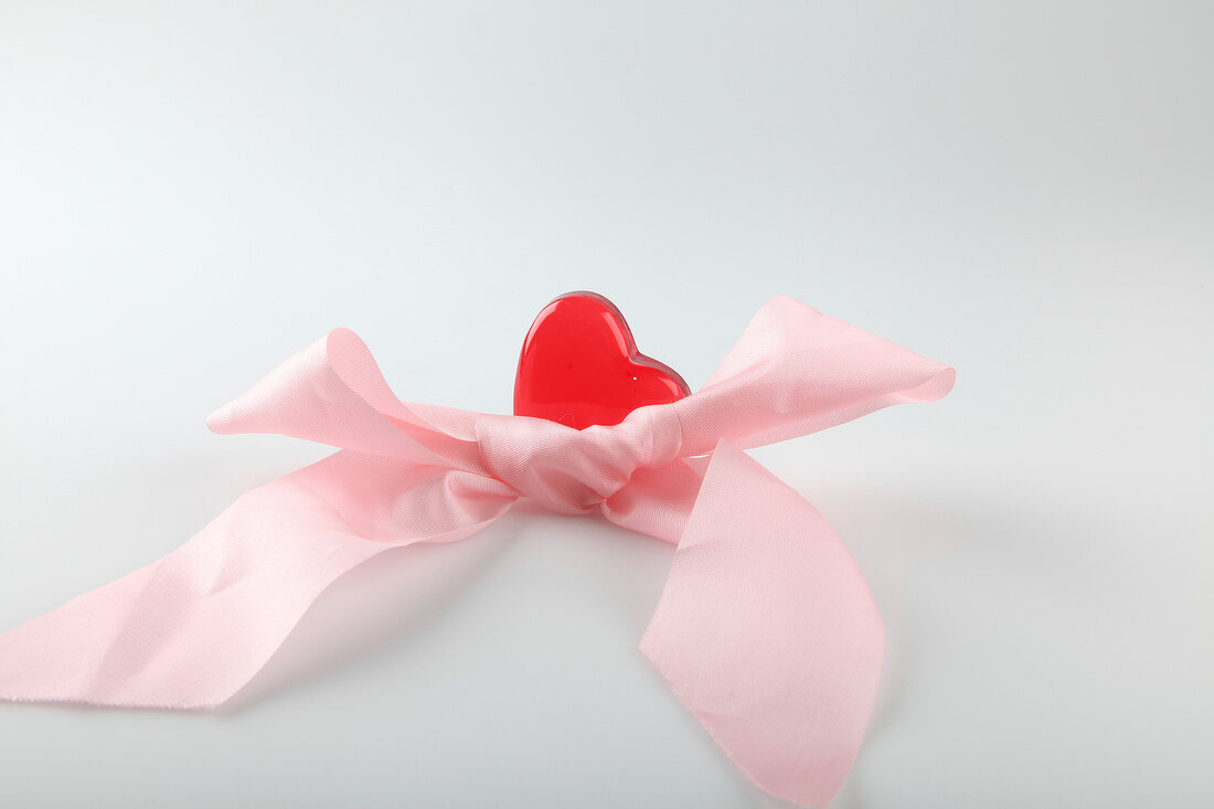 Close-up of pink ribbon with heart on white background