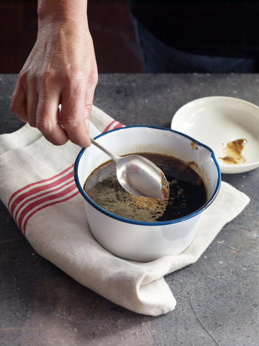 Close-up of removing skim from jelly in bowl