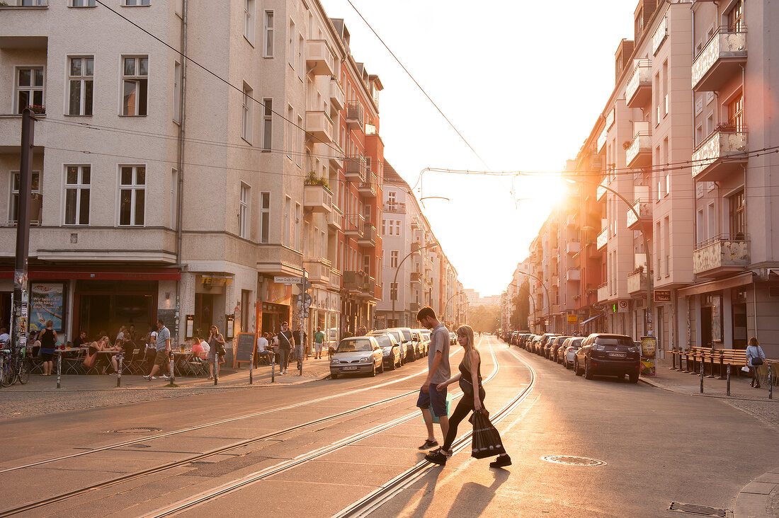 Couple walking across the tramway track at sunset in Friedrichshain, Berlin, Germany