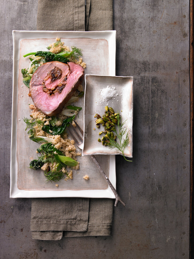 Plate of spiced lamb with pistachio couscous on napkin