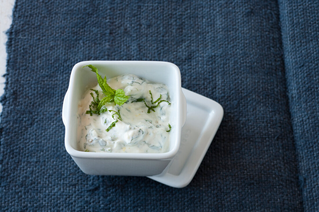 Bowl of yogurt and mint sauce on gray background