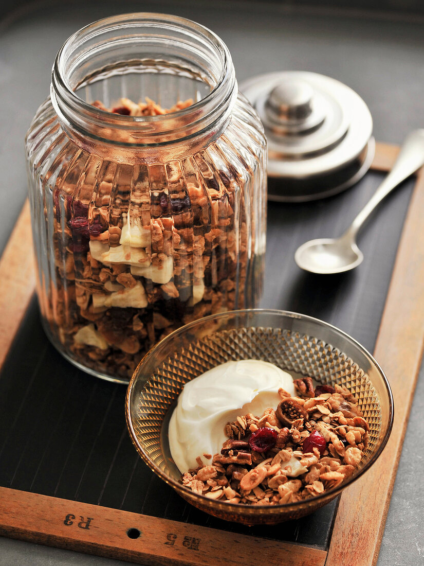 Autumn cereal with maple syrup and nuts in glass bowl and jar
