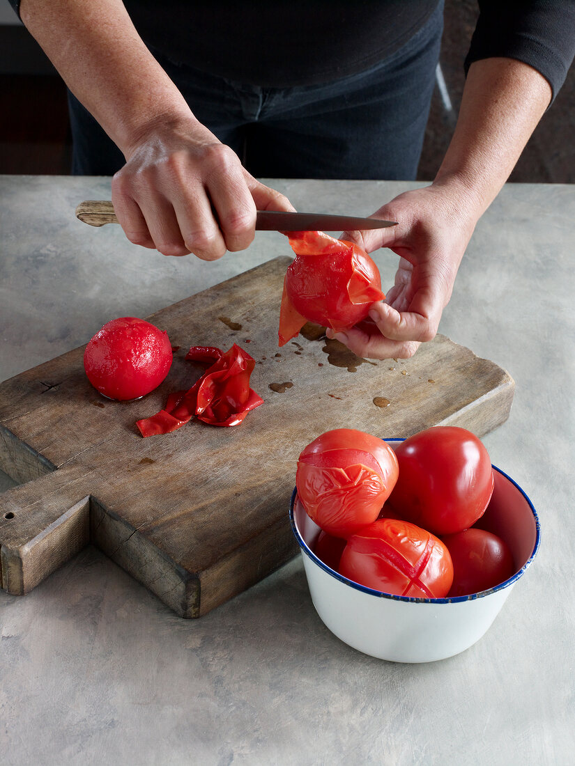 Close-up of tomatoes being peeled on wooden board