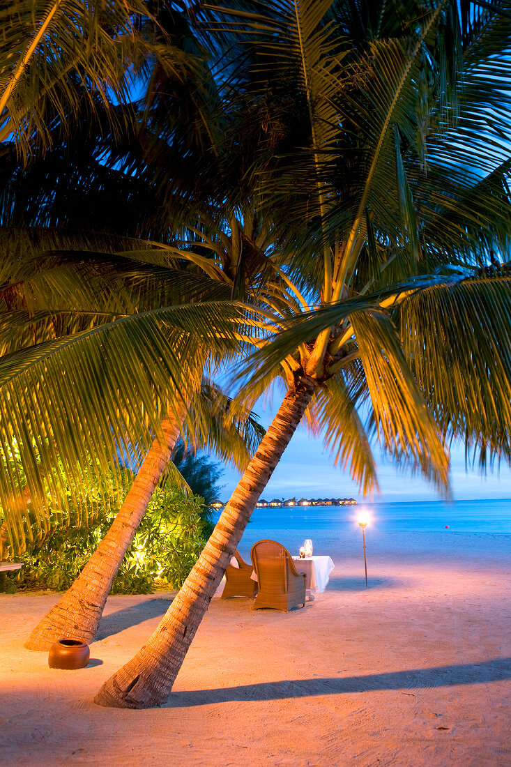 Tables laid on beach at dusk in Veligandu Island Resort, Maldives