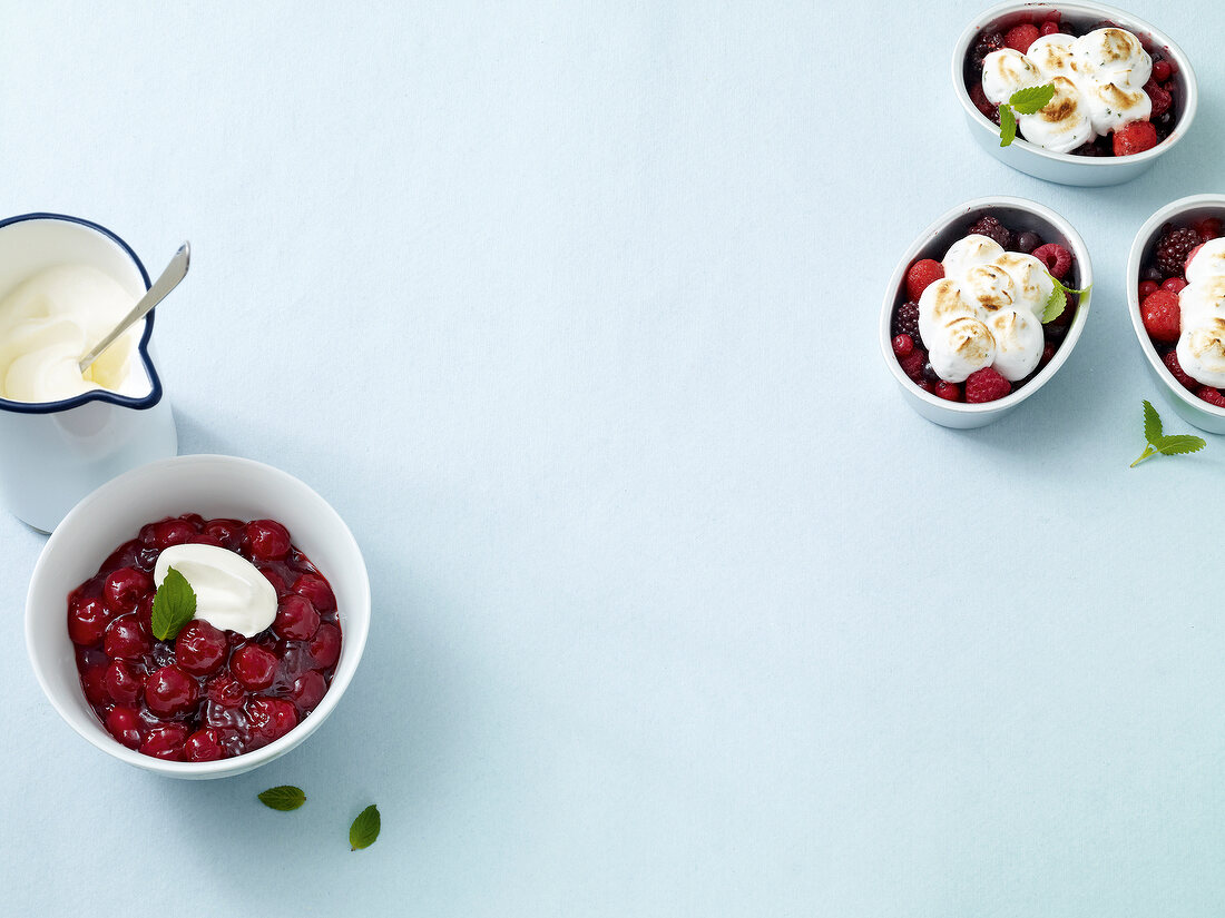 Cherry compote with cream, berries and lemon meringue on white background