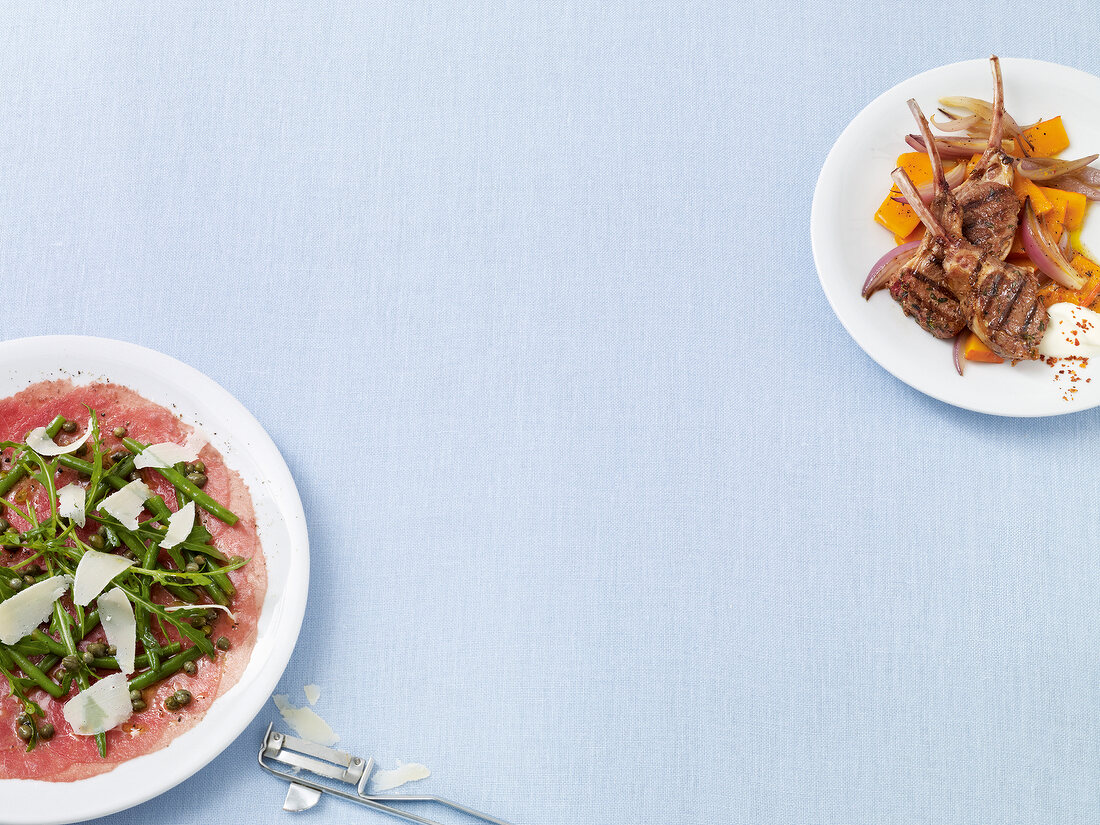 Carpaccio with green beans and lamb chops with pumpkin on plates