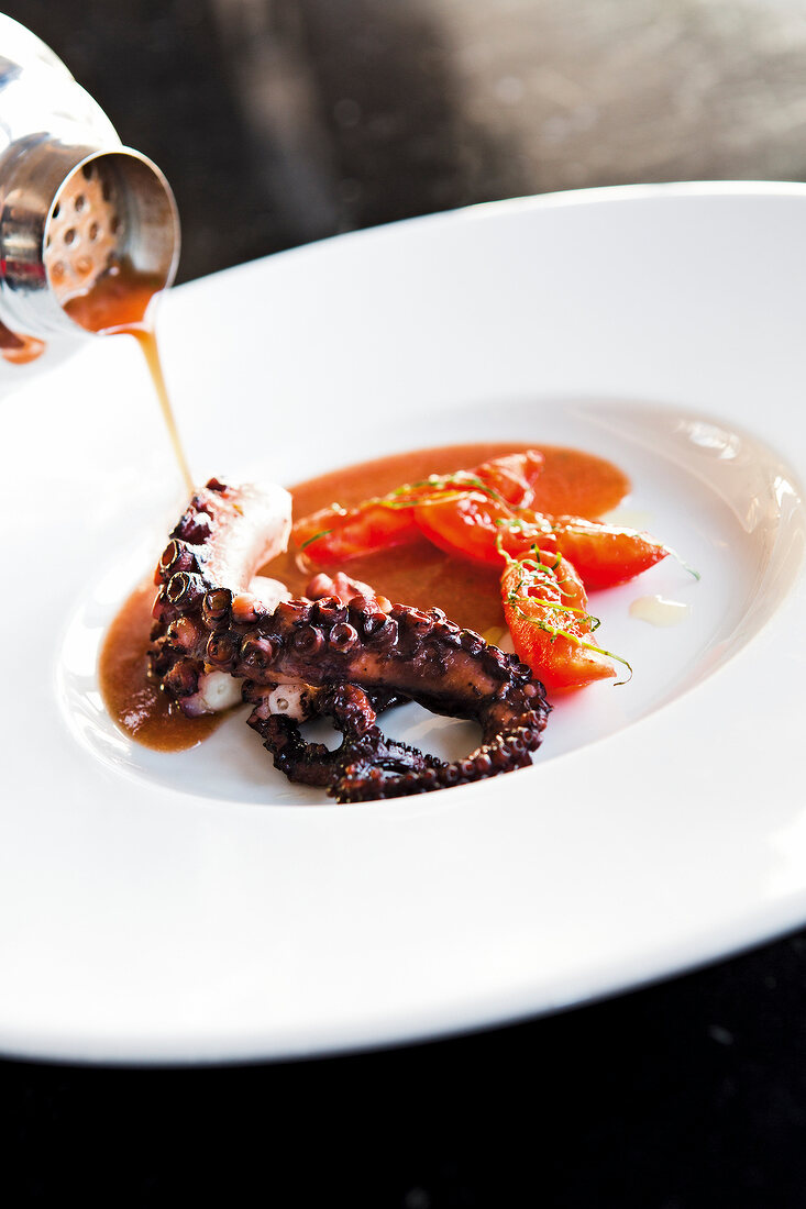 Close-up of smoked octopus being poured with tomato broth