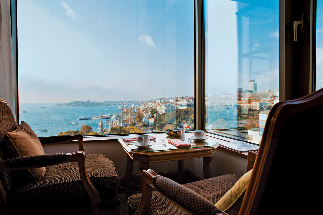 Chairs and table in front of widow overlooking cityscape and sea in Istanbul, Turkey