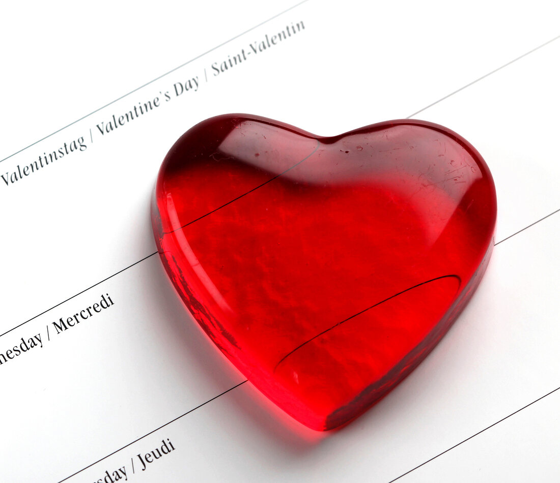 Red glass heart on calendar with date of 14th February
