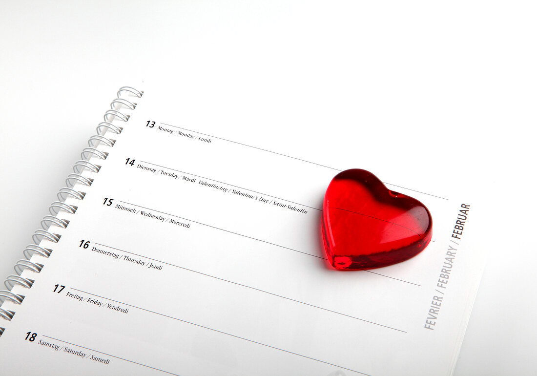 Red glass heart on calendar with date of 14th February