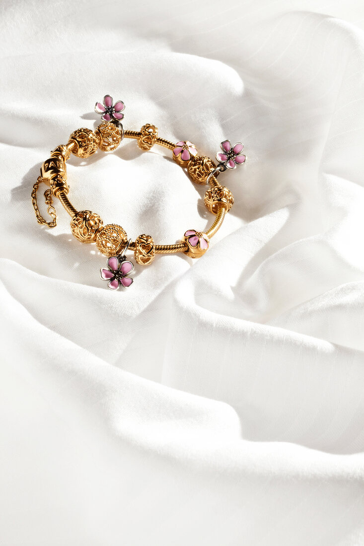 Gold Pandora bracelet on white silk sheet