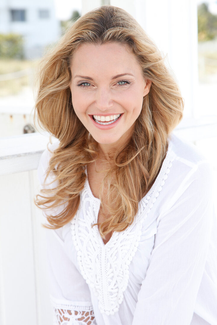 Portrait of happy woman wearing white tunic blouse, smiling