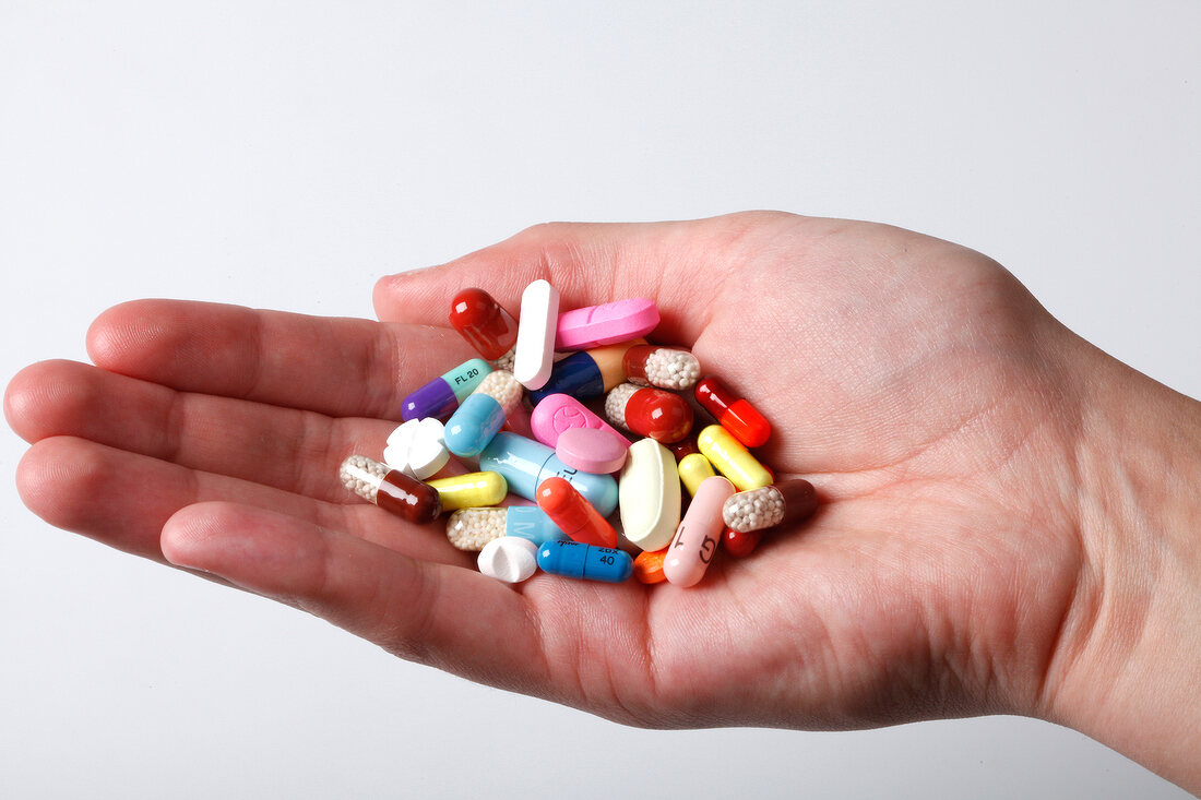 Close-up of pills and tablets in hand on white background