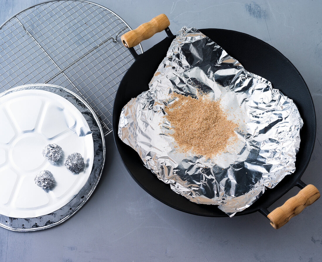 Wood flour on aluminium foil in wok with grill