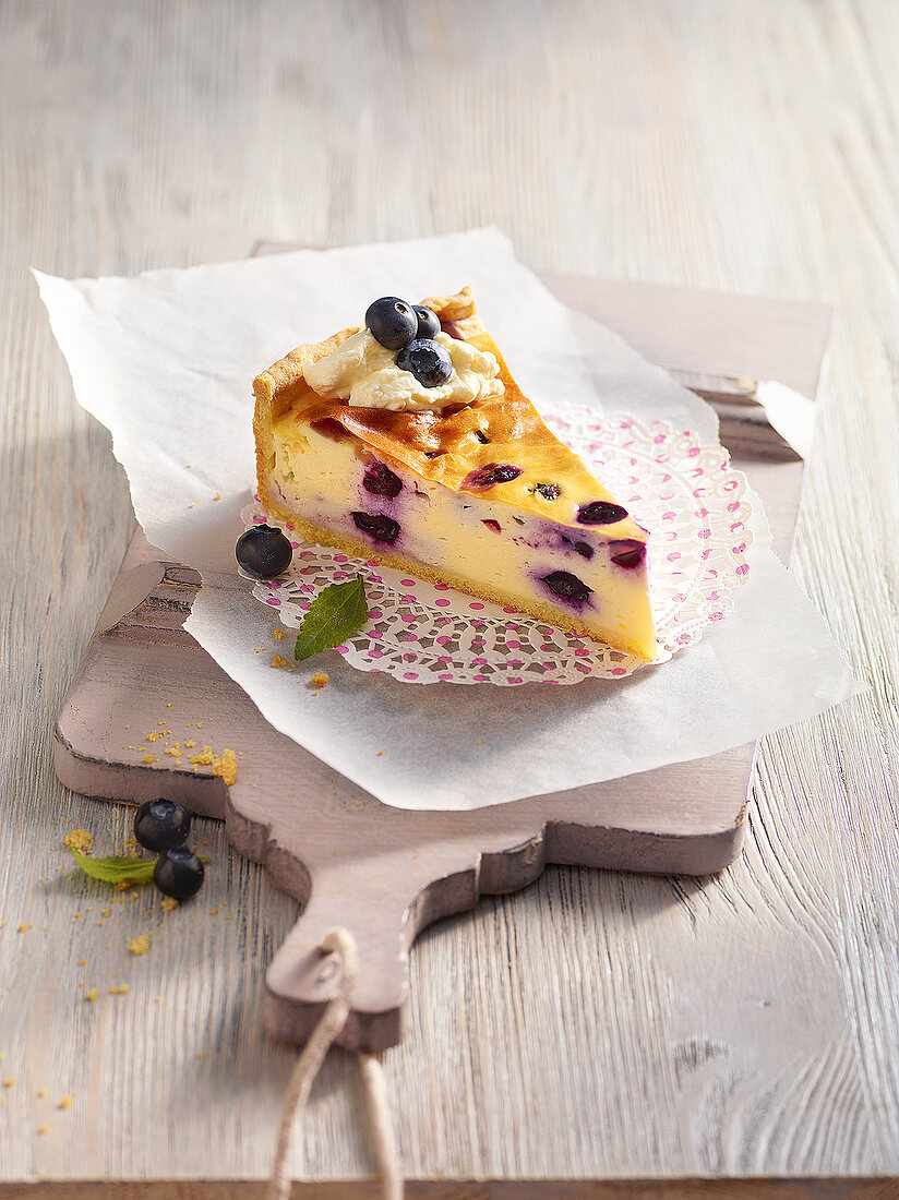 Slice of cheese cake with blueberries on wooden tray