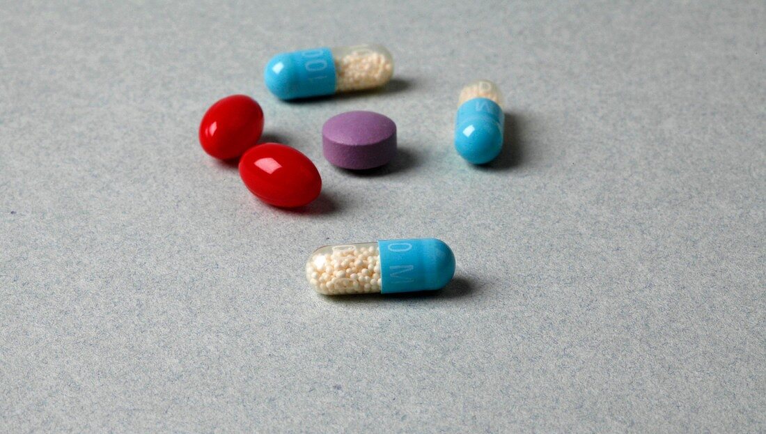 Close-up of various colourful tablets and capsules on gray background