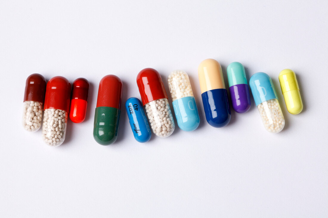 Various coloured capsules arranged in a row on white background